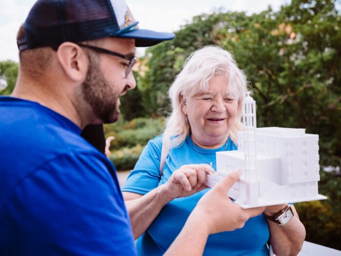 Dobrovolník Open House Praha s 3D modelem budovy asistuje návštěvníci se zrakovým postižením