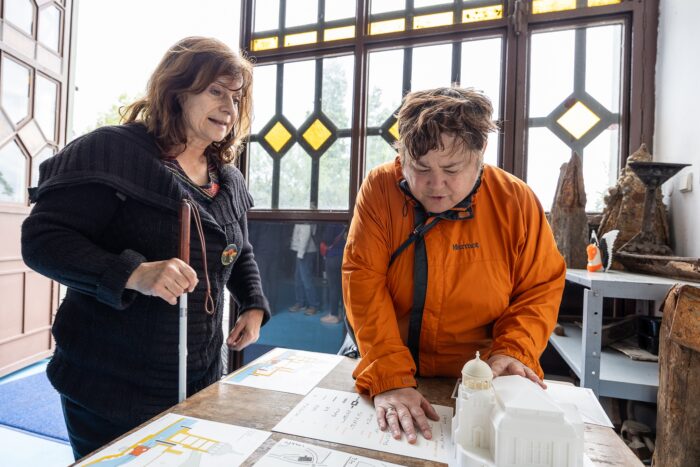 Dvě nevidomé návštěvnice hmatem prozkoumávají 3D model elektrárny Štvanice, Open House Praha 2025